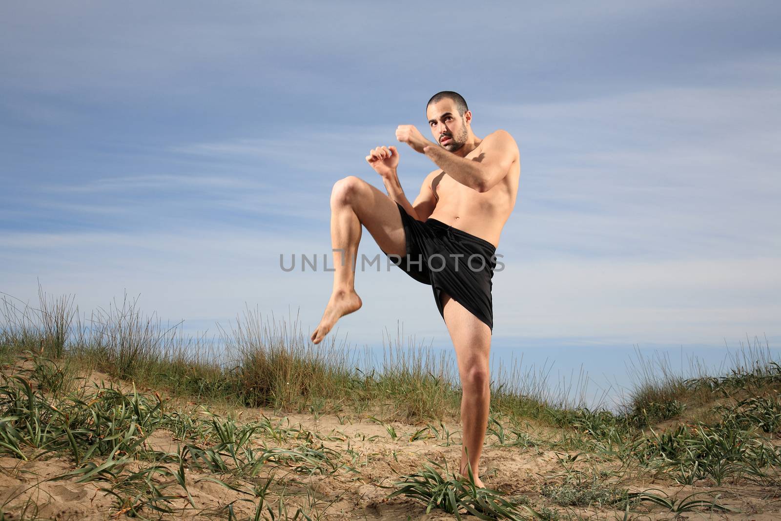 young martial arts instructor exercising on a sand hill