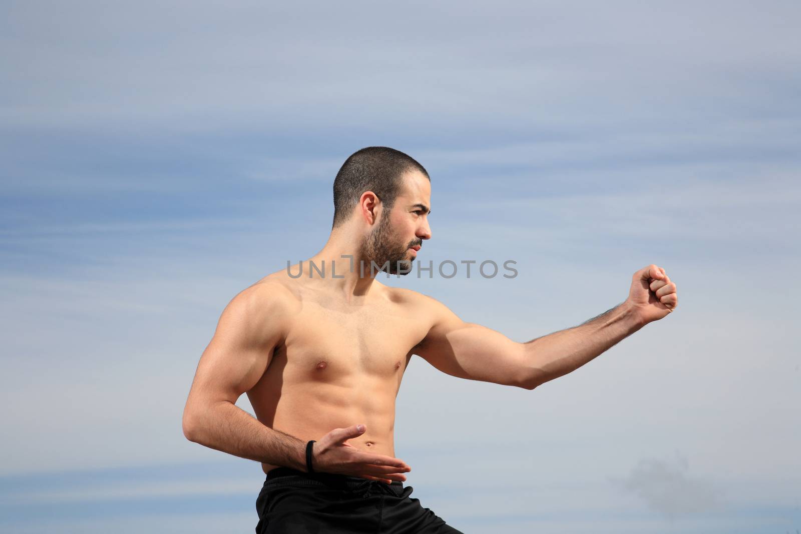 young martial arts instructor exercising on a sand hill