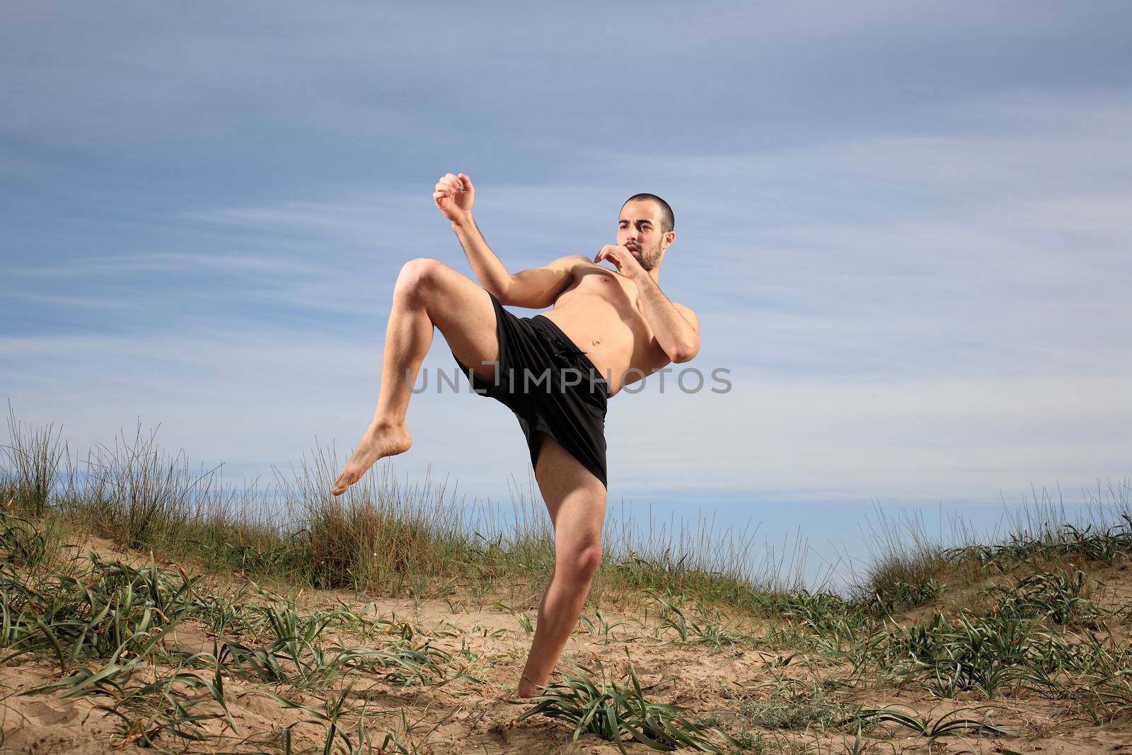 young martial arts instructor exercising on a sand hill