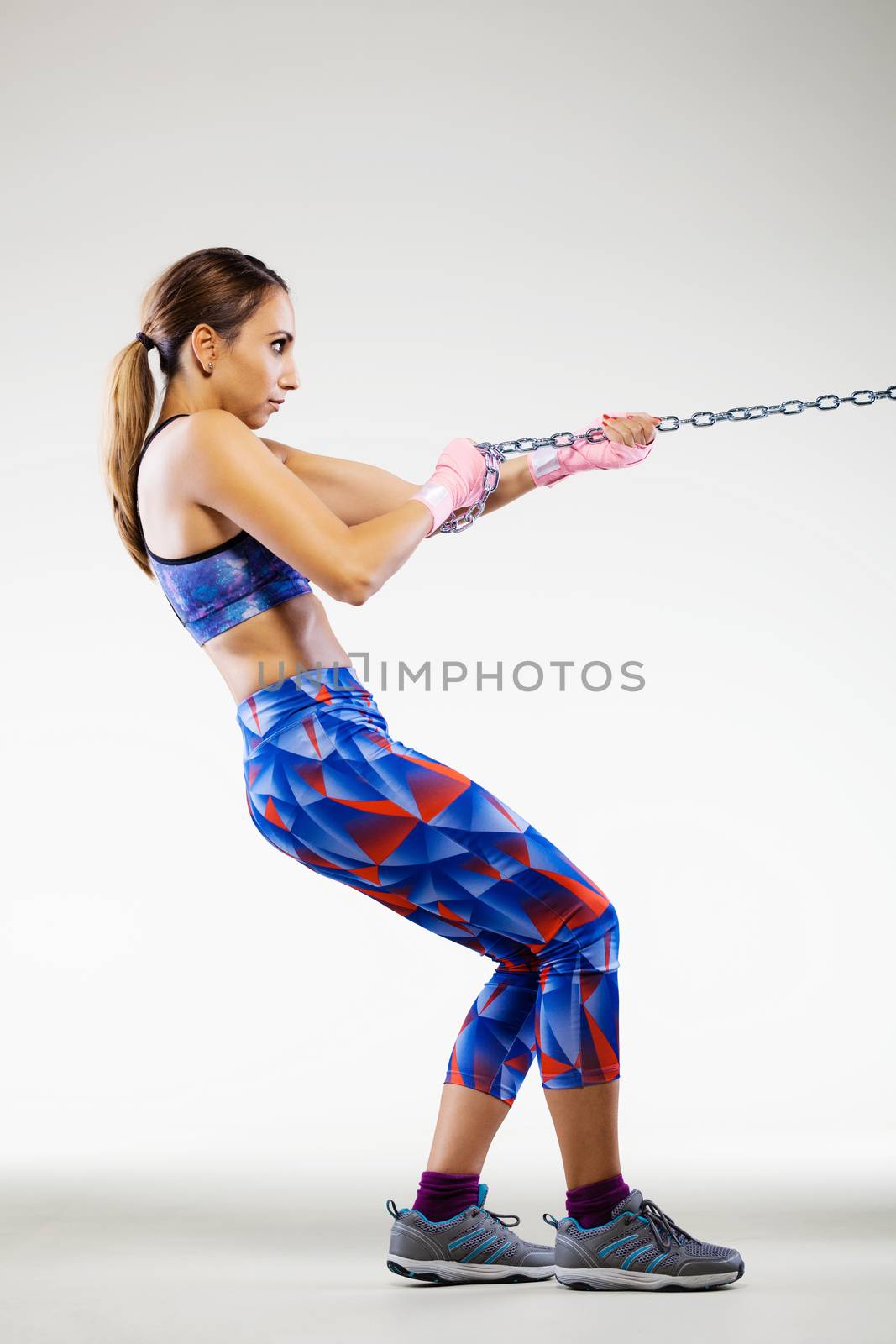 girl kickboxer pulling a chain with pink hand wraps
