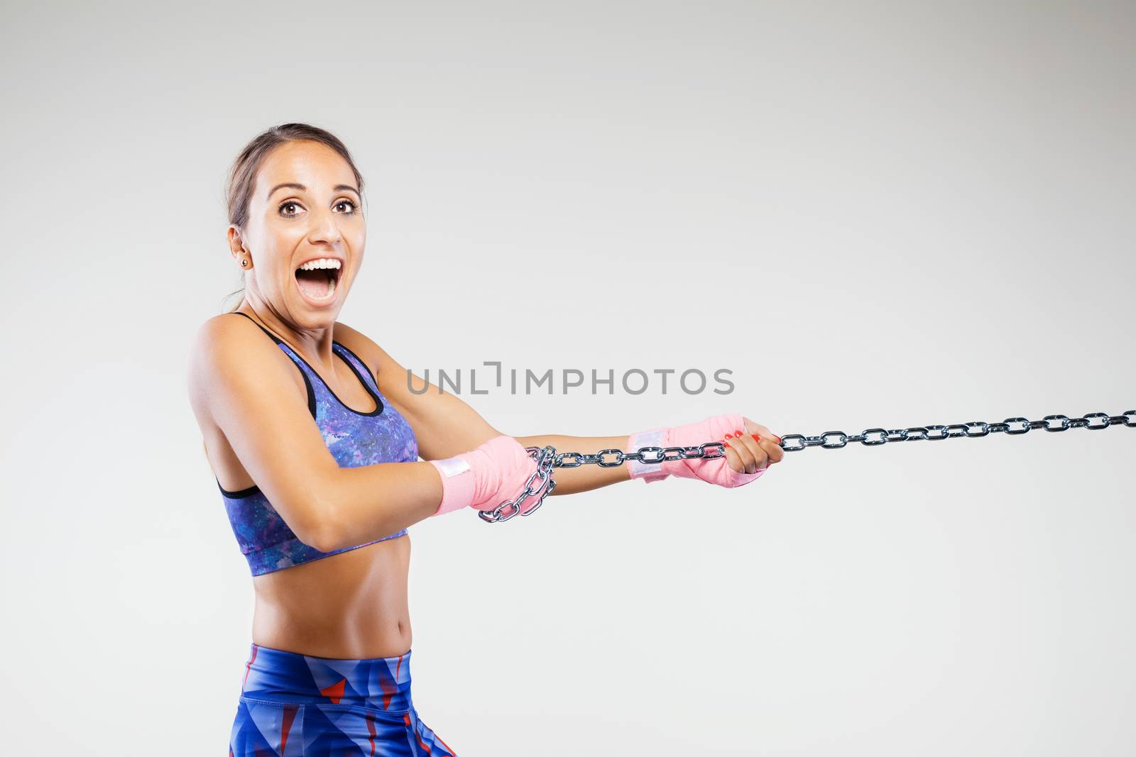 girl kickboxer pulling a chain with pink hand wraps