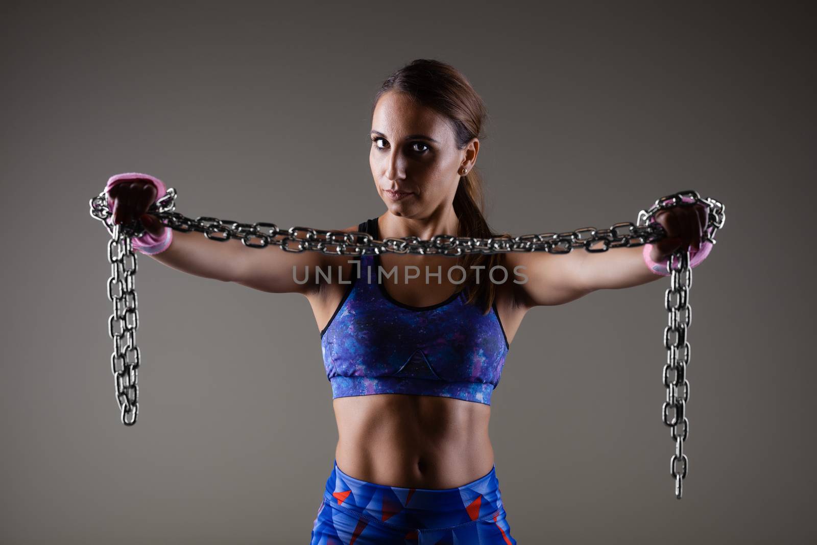 girl kickboxer holding a chain with pink hand wraps