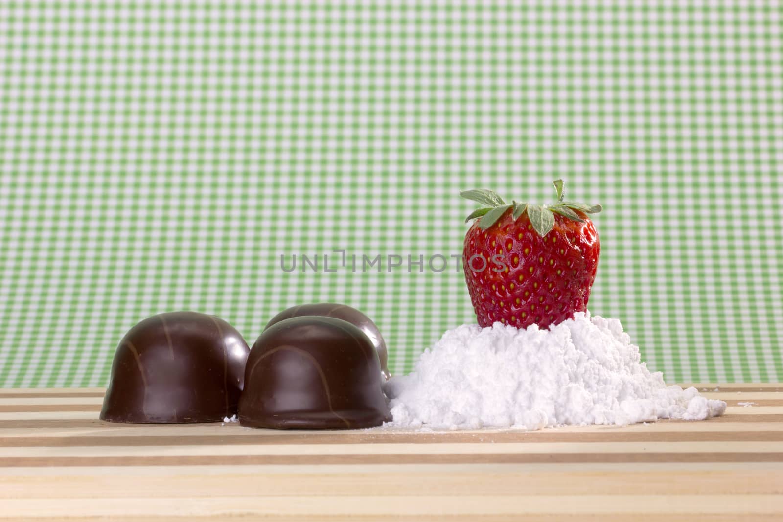 closeup of fresh strawberry on sugar powder and chocolates