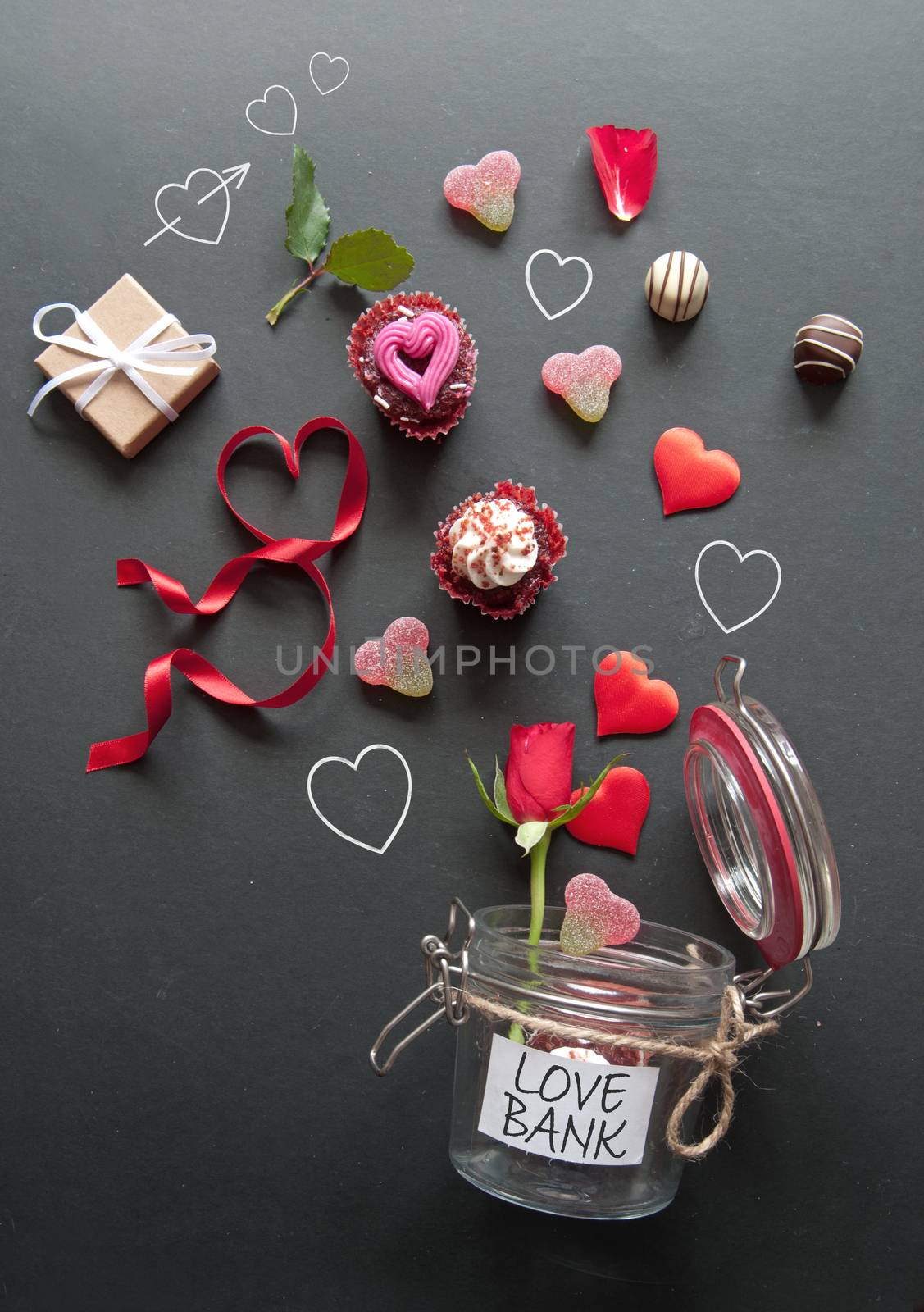 Hearts, cupcakes, roses and gifts pouring out of a love bank jar on a chalkboard