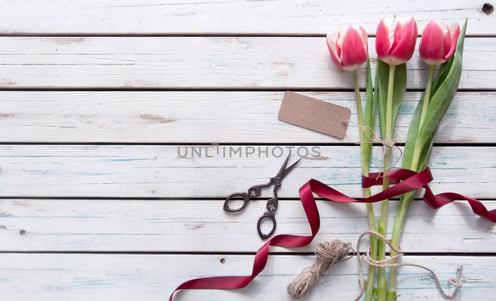 Pink tulips on a wooden background wtih gift tag