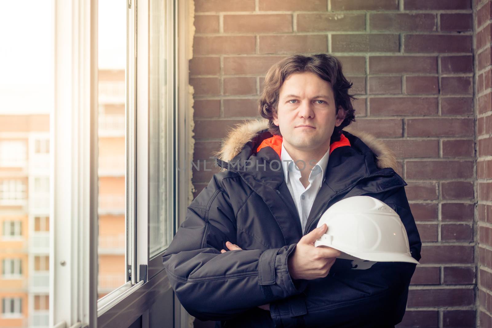 Architect, engineer. Industrial worker. Man builder. Business, building, industry, technology - builder concept. Builder in protective clothing and helmet in his arms. Male builder. Soft focus toned