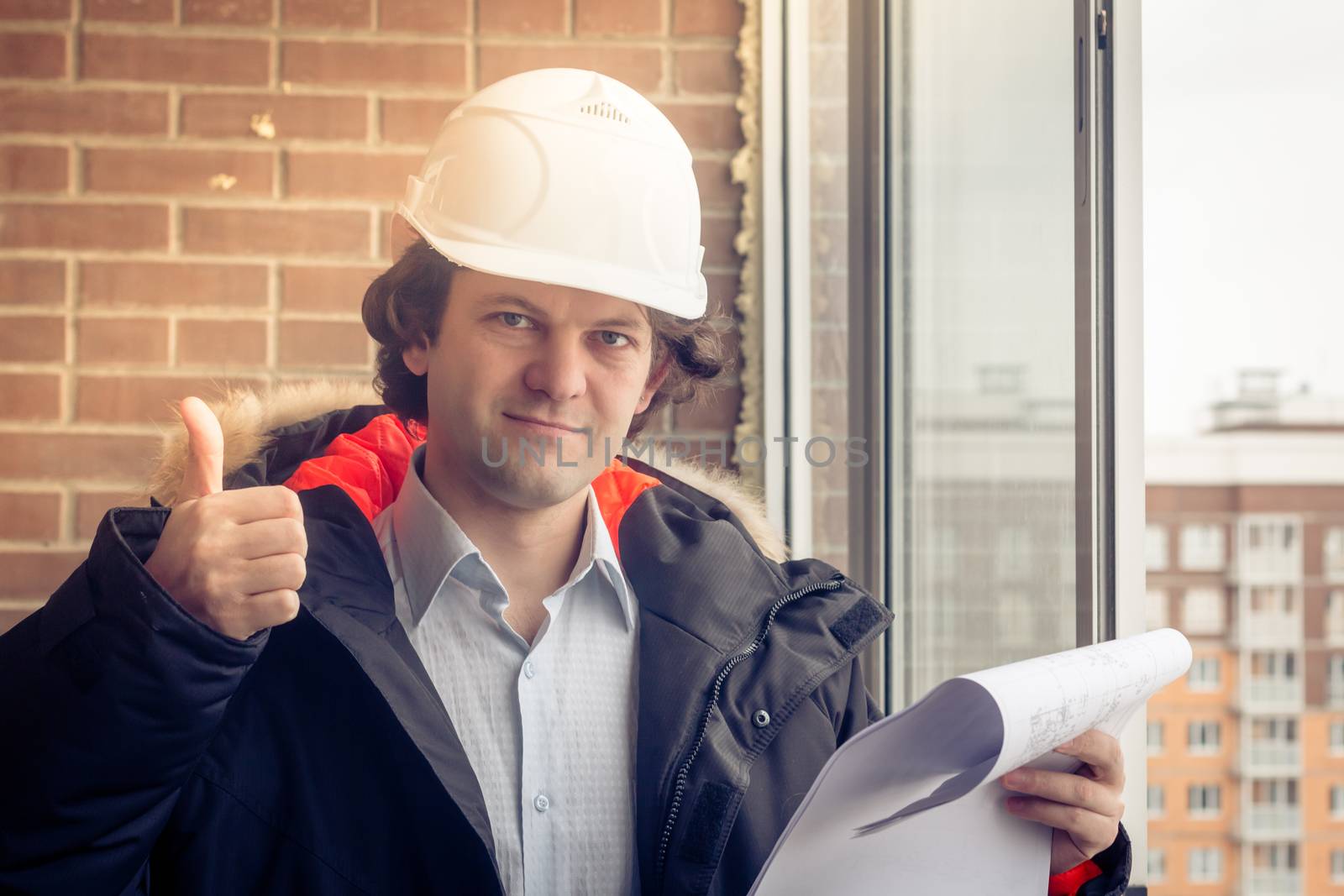 A construction worker gives you the thumbs up sign, signaling that everything is going well or the instruction was understood. Soft focus, toned