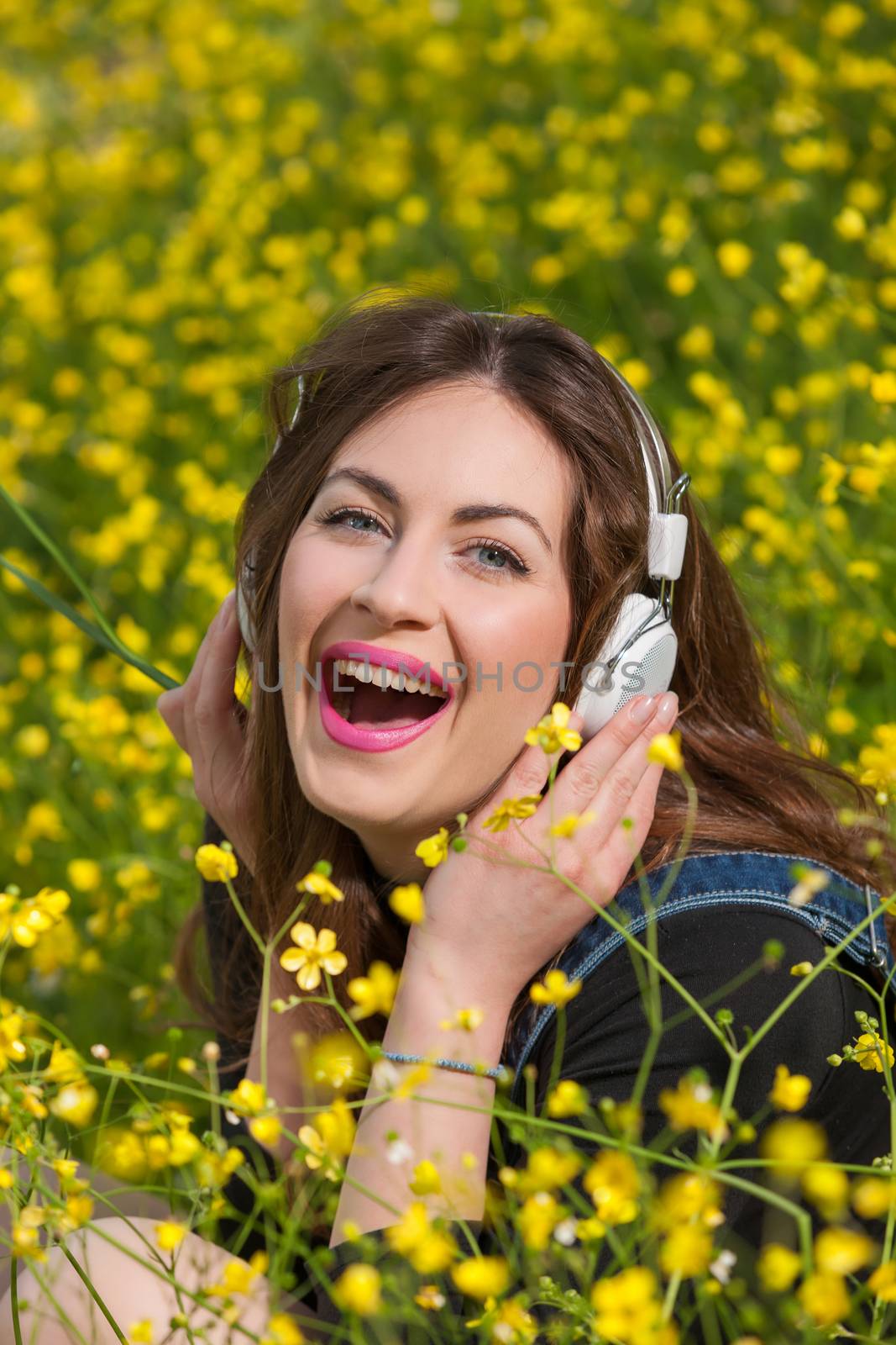 portrait of a beautiful young girl with headphones among yellow flowers of a garden