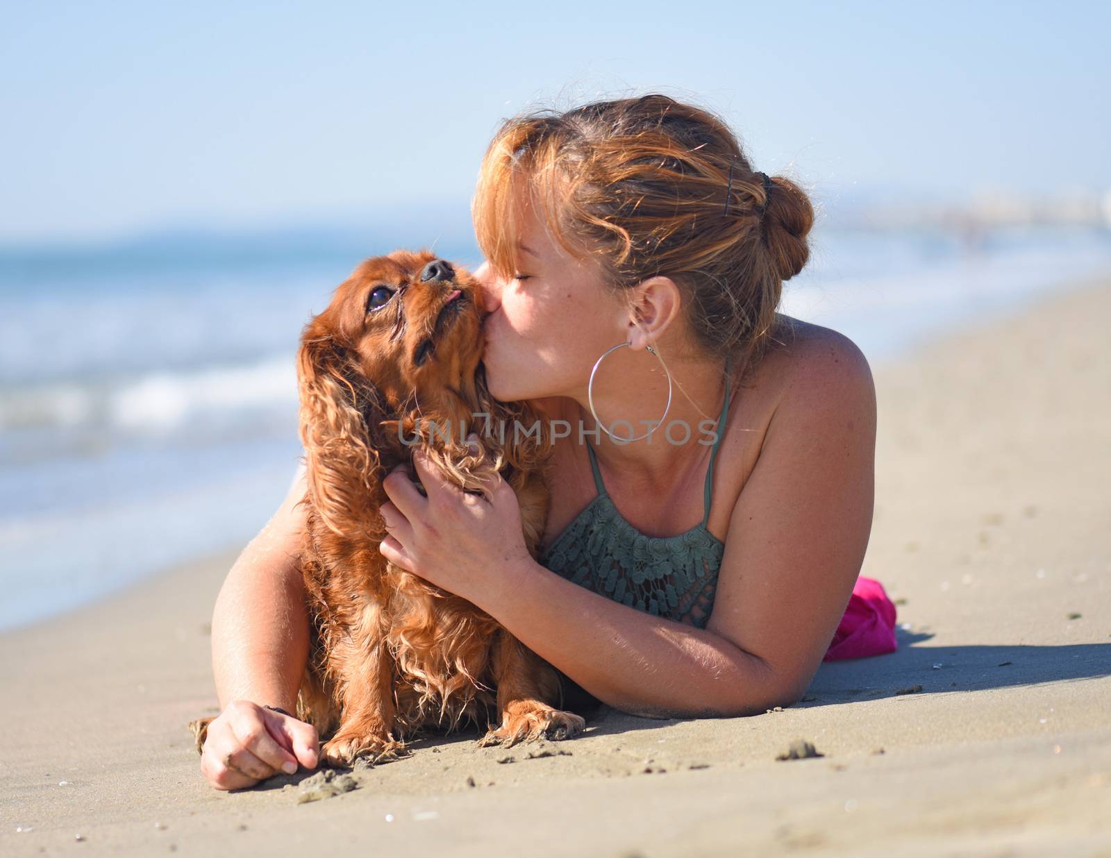 woman and dog kissing on the beach