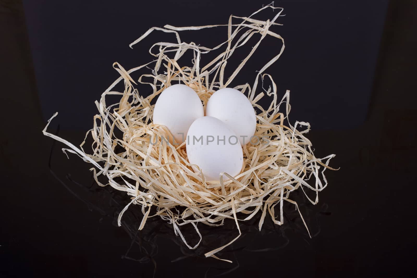 Three chicken eggs in the nest like On a black background