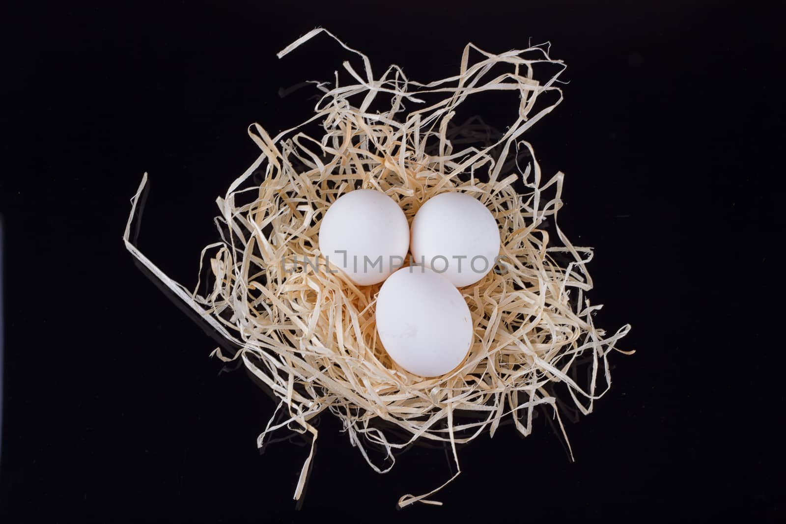 Three chicken eggs in the nest like On a black background