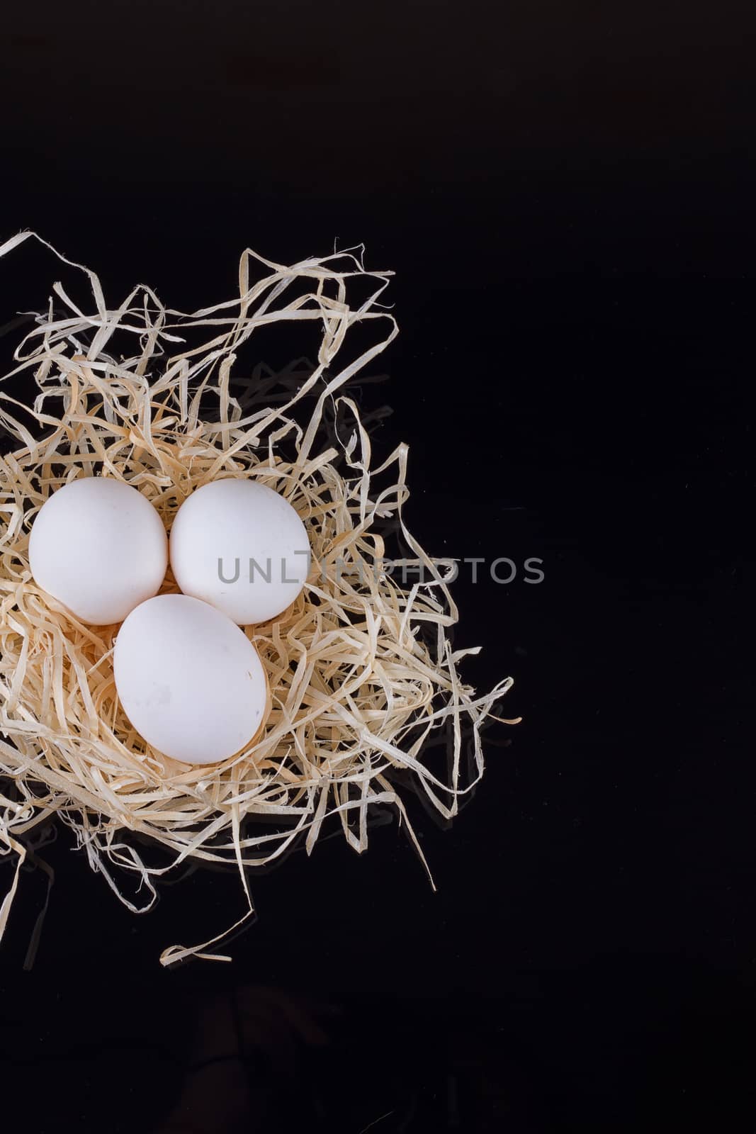 Three chicken eggs in the nest like On a black background