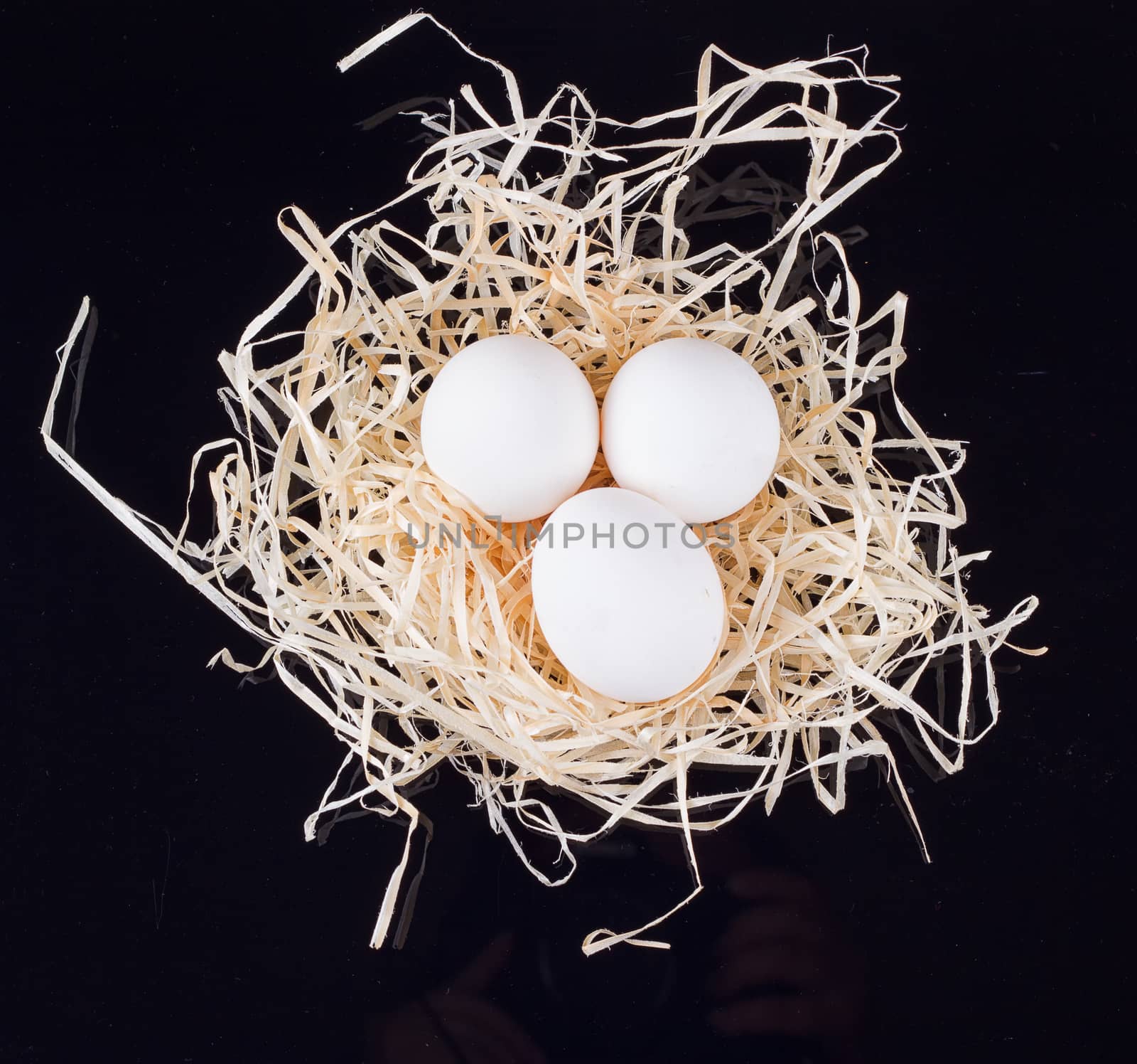 Three chicken eggs in the nest like On a black background