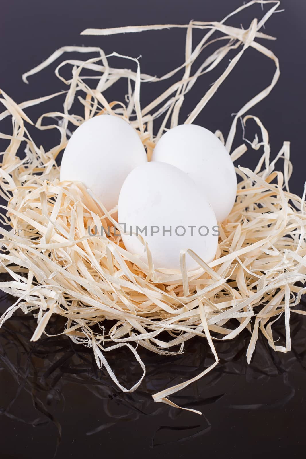 Three chicken eggs in the nest like On a black background