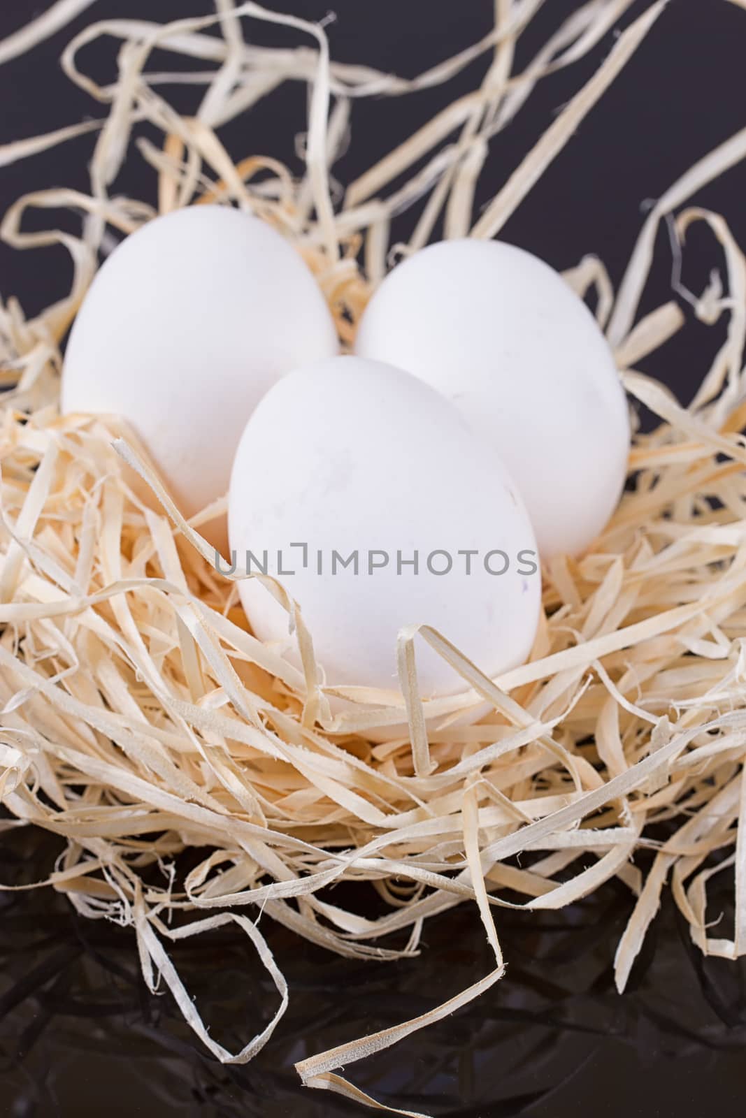 Three chicken eggs in the nest like On a black background