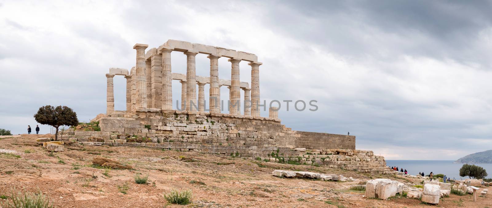 Ruins of an ancient Greek temple of Poseidon under dramatic cloudy sky, Cape Sounion, Greece