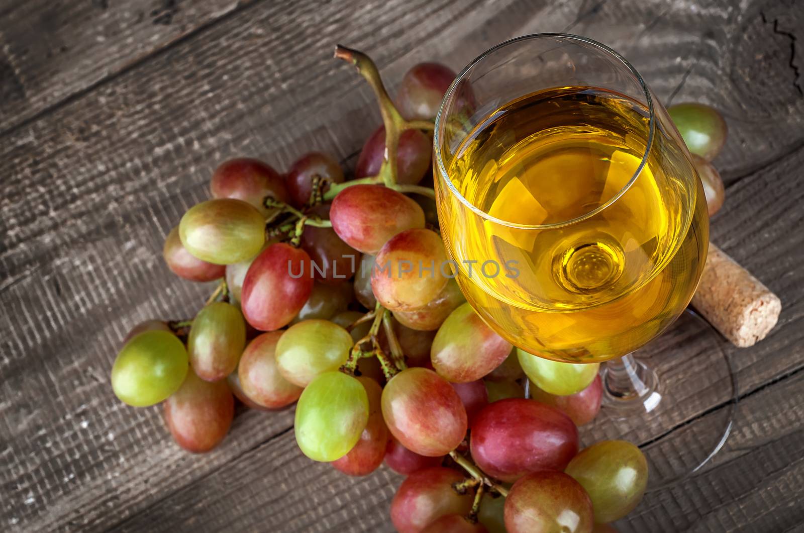 Glass of white wine with a cluster of grapes by Cipariss