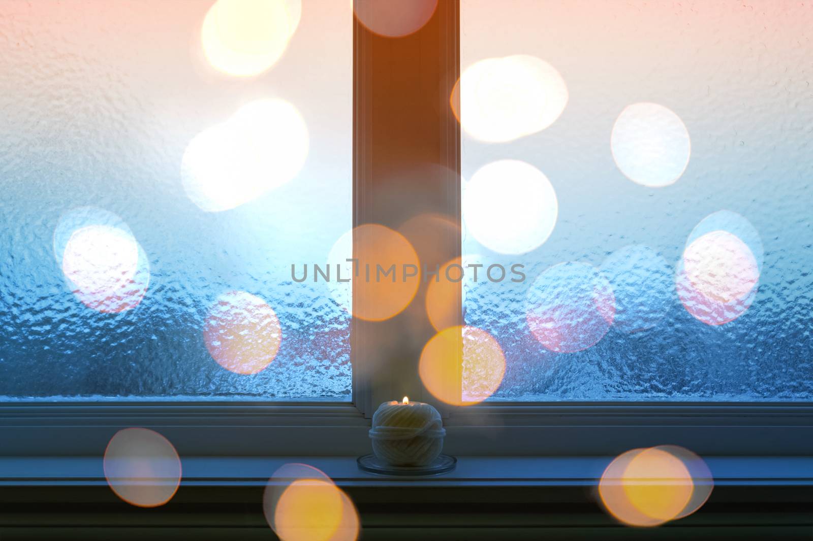 Frosted window, bokeh lights, and burning candle by anikasalsera