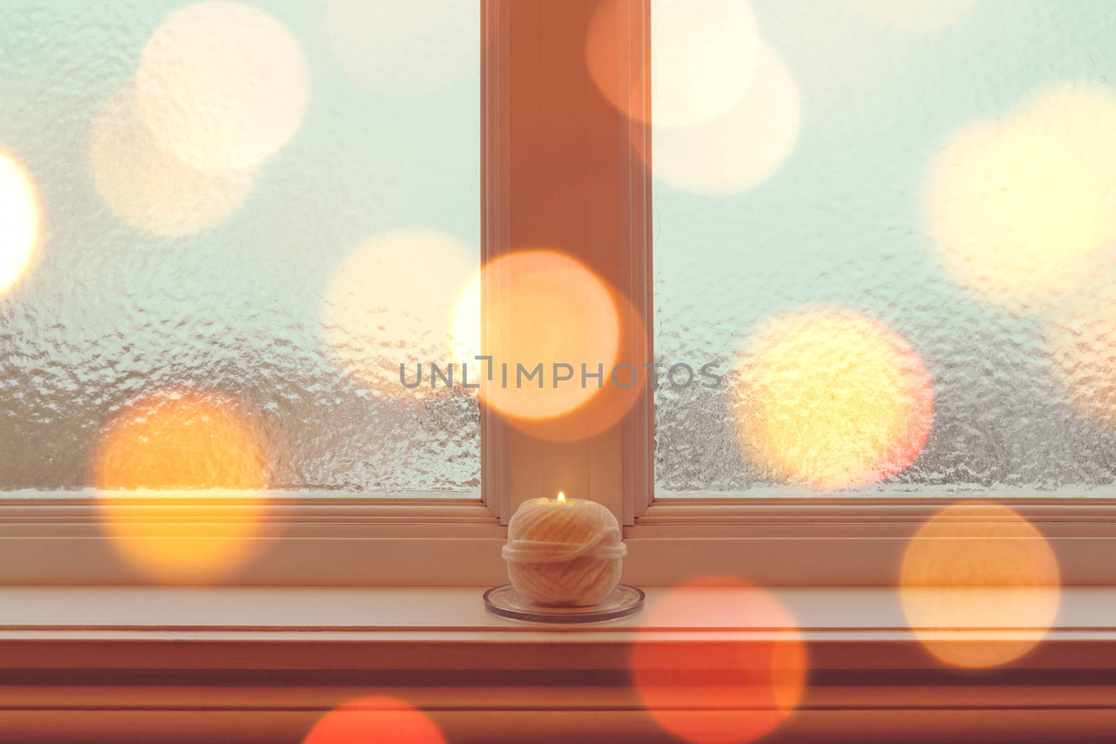 Cozy candle on a windowsill in golden light by anikasalsera