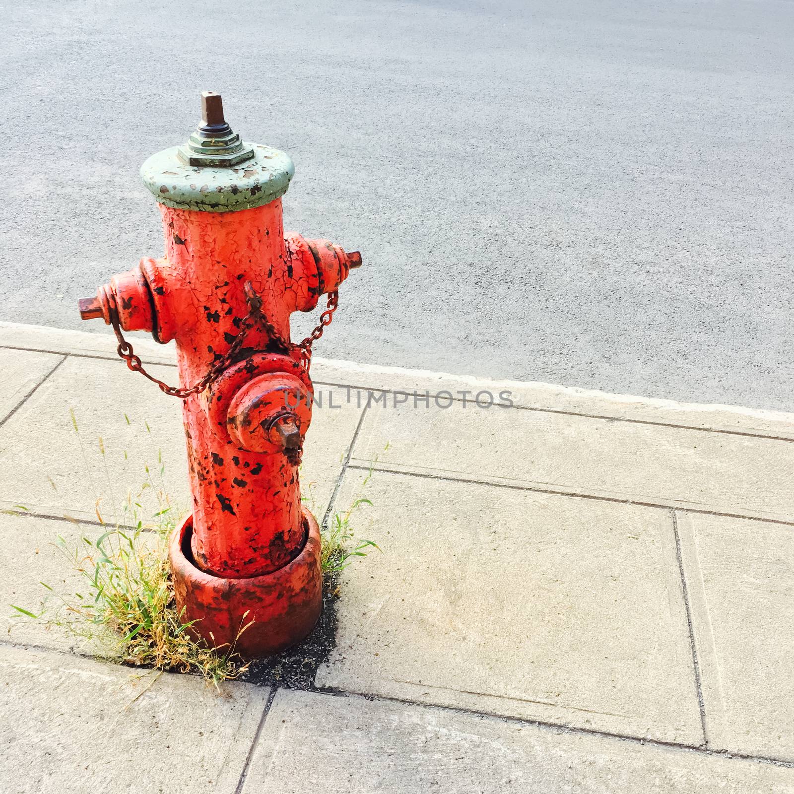 Red fire hydrant on a sidewalk of an urban street.