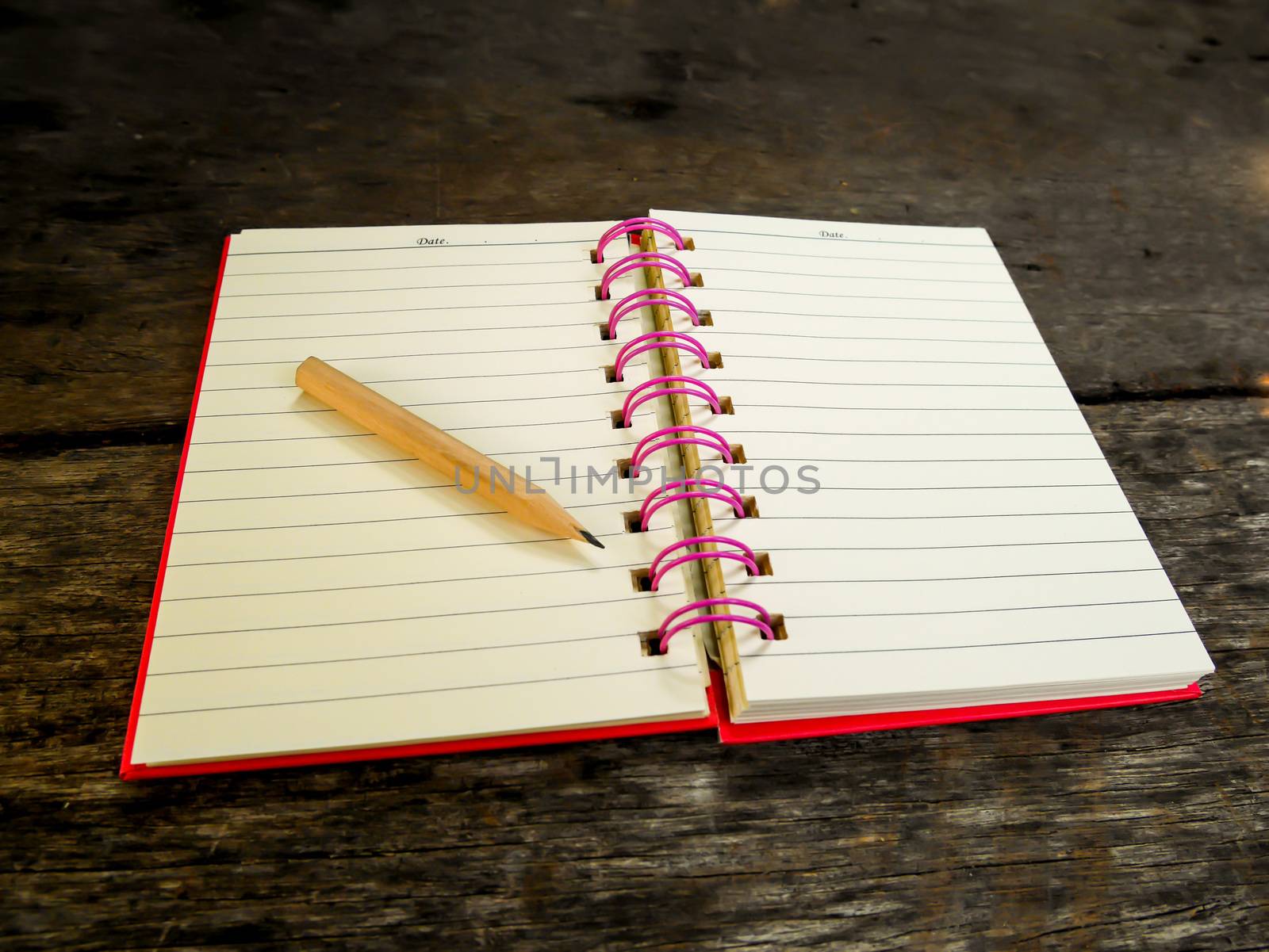 Note book with pencil on wooden table