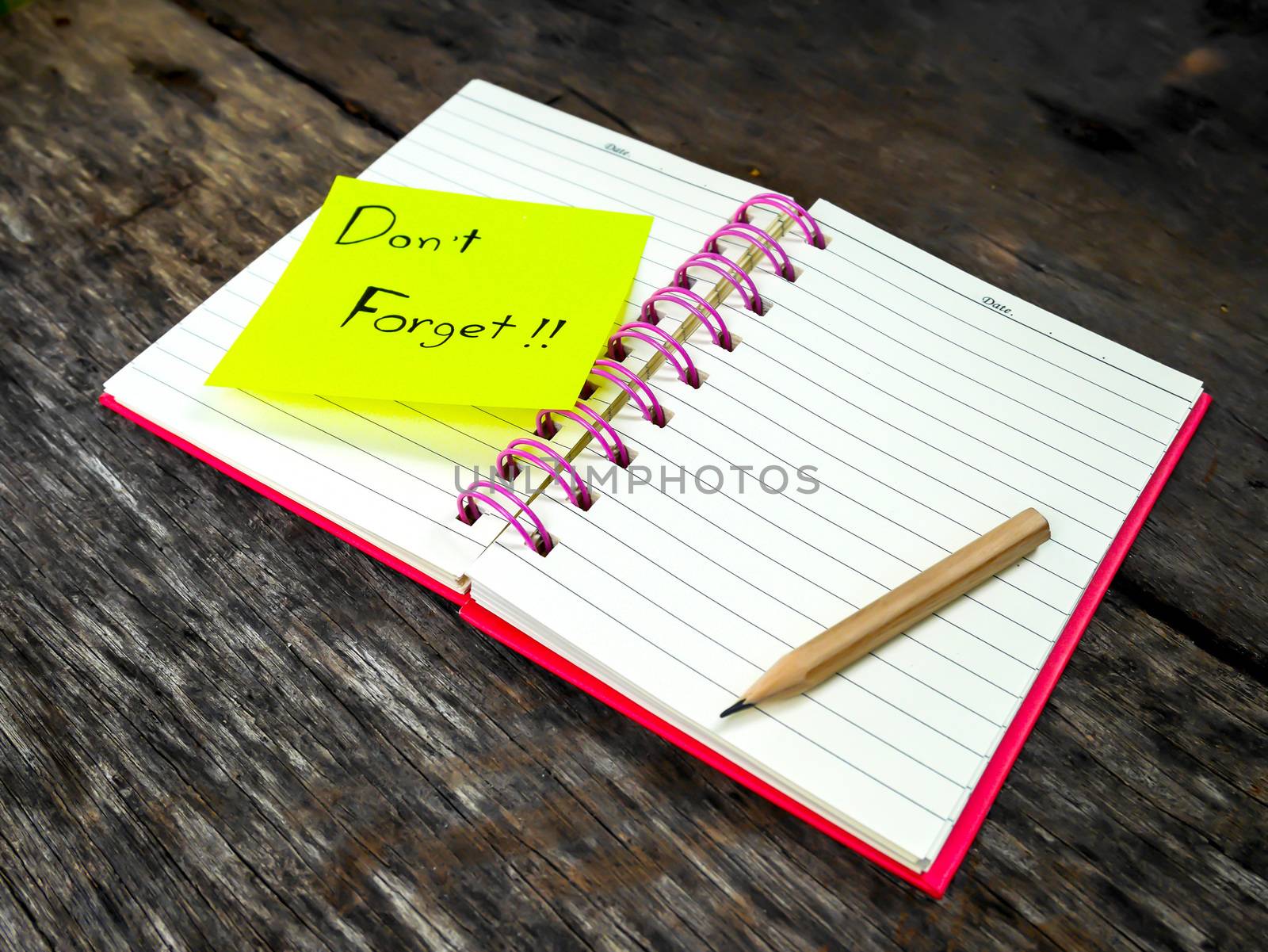 Reminder paper note in note book on wooden table with selective focus