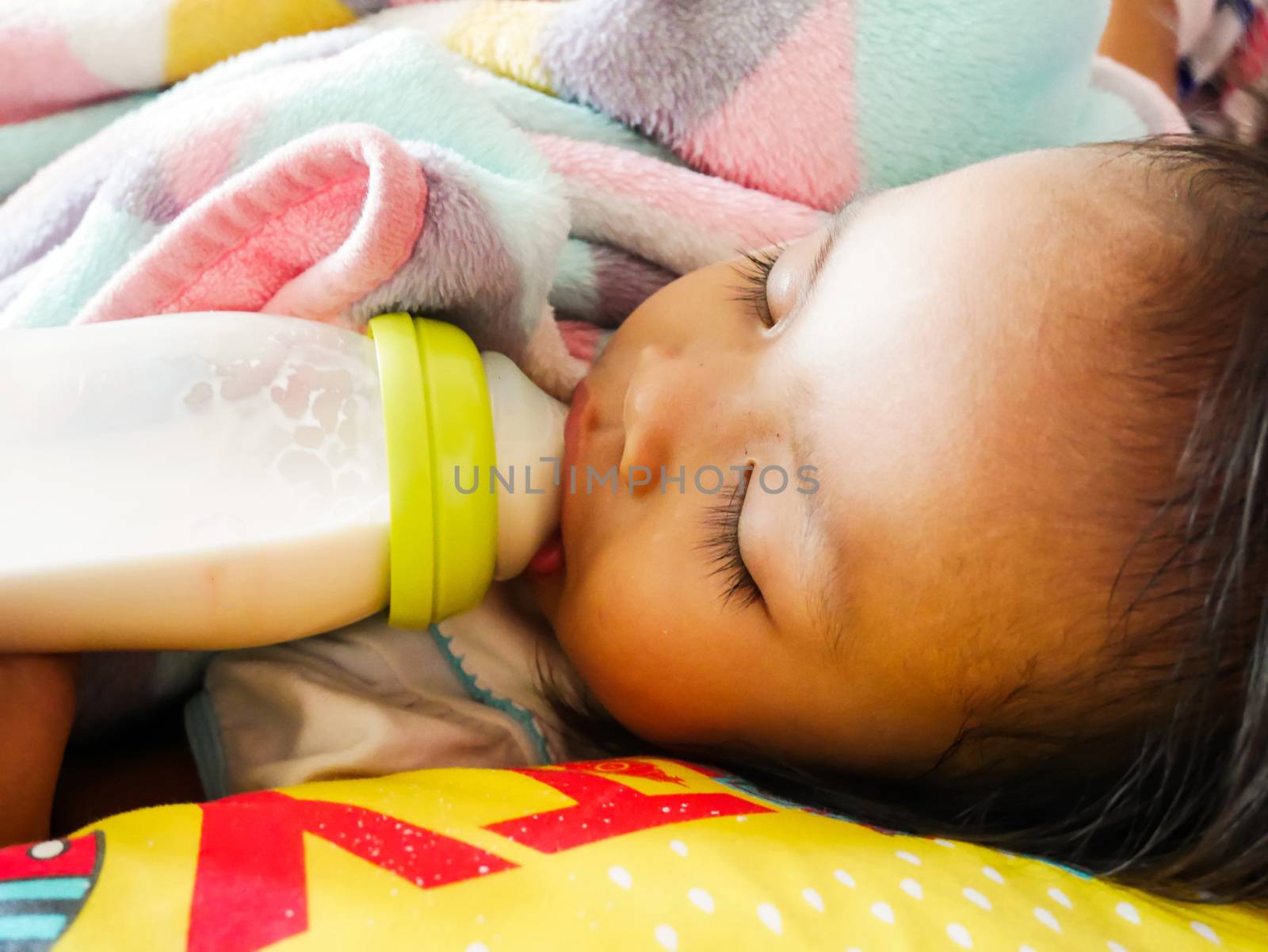 Asian baby sleepin on her bed and drinking milk from bottle, it so cute