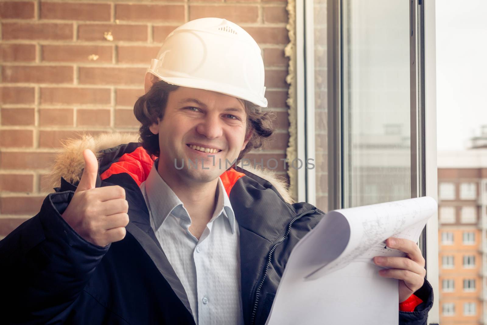 A handsome construction worker giving a thumbs-up sign. Authentic construction worker on actual construction site. Soft focus, toned