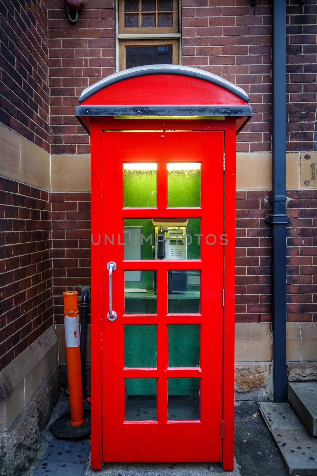 Vintage UK red phone booth in front of a brick wall