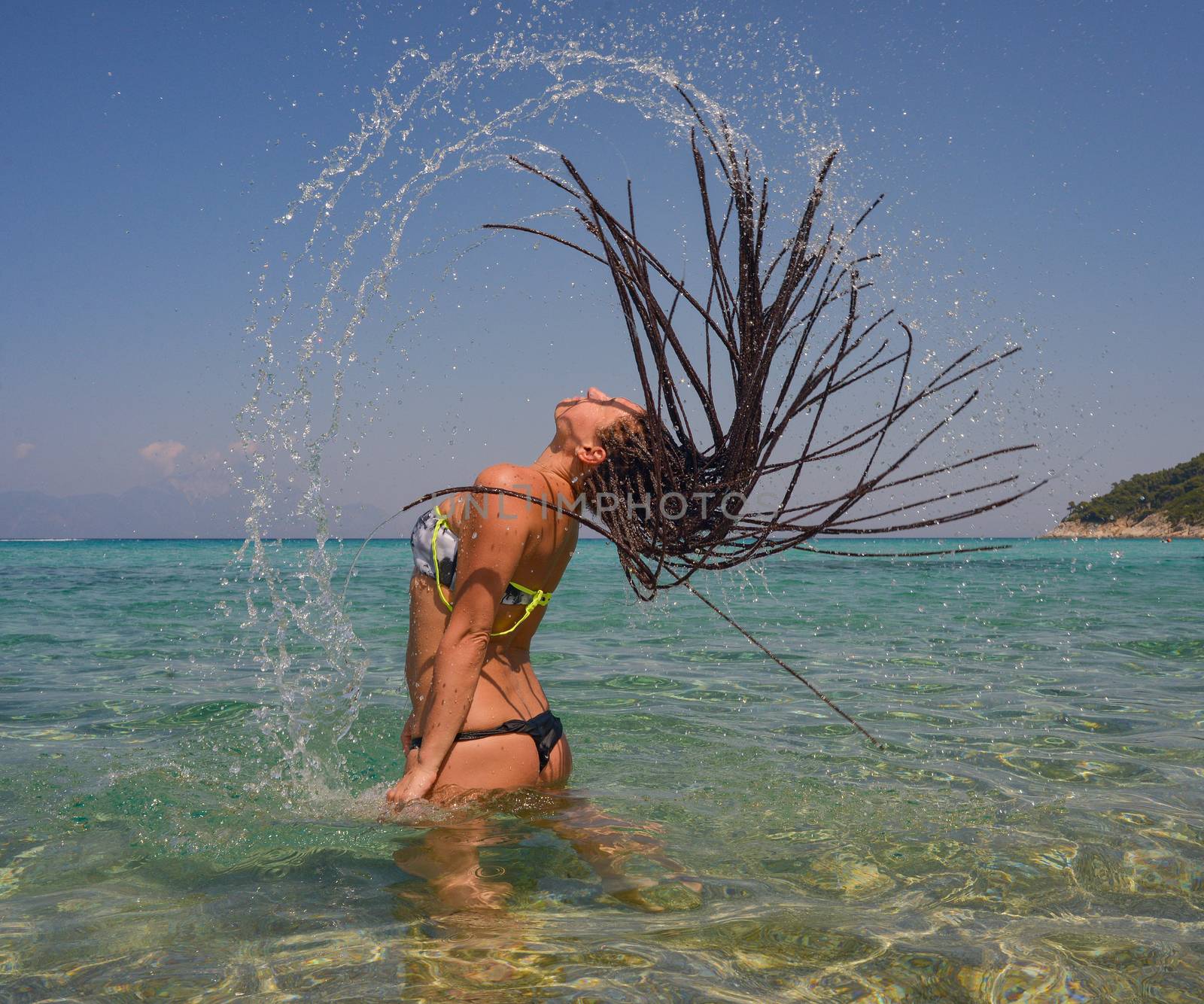 Beautiful girl splashing water with her hair in the sea.