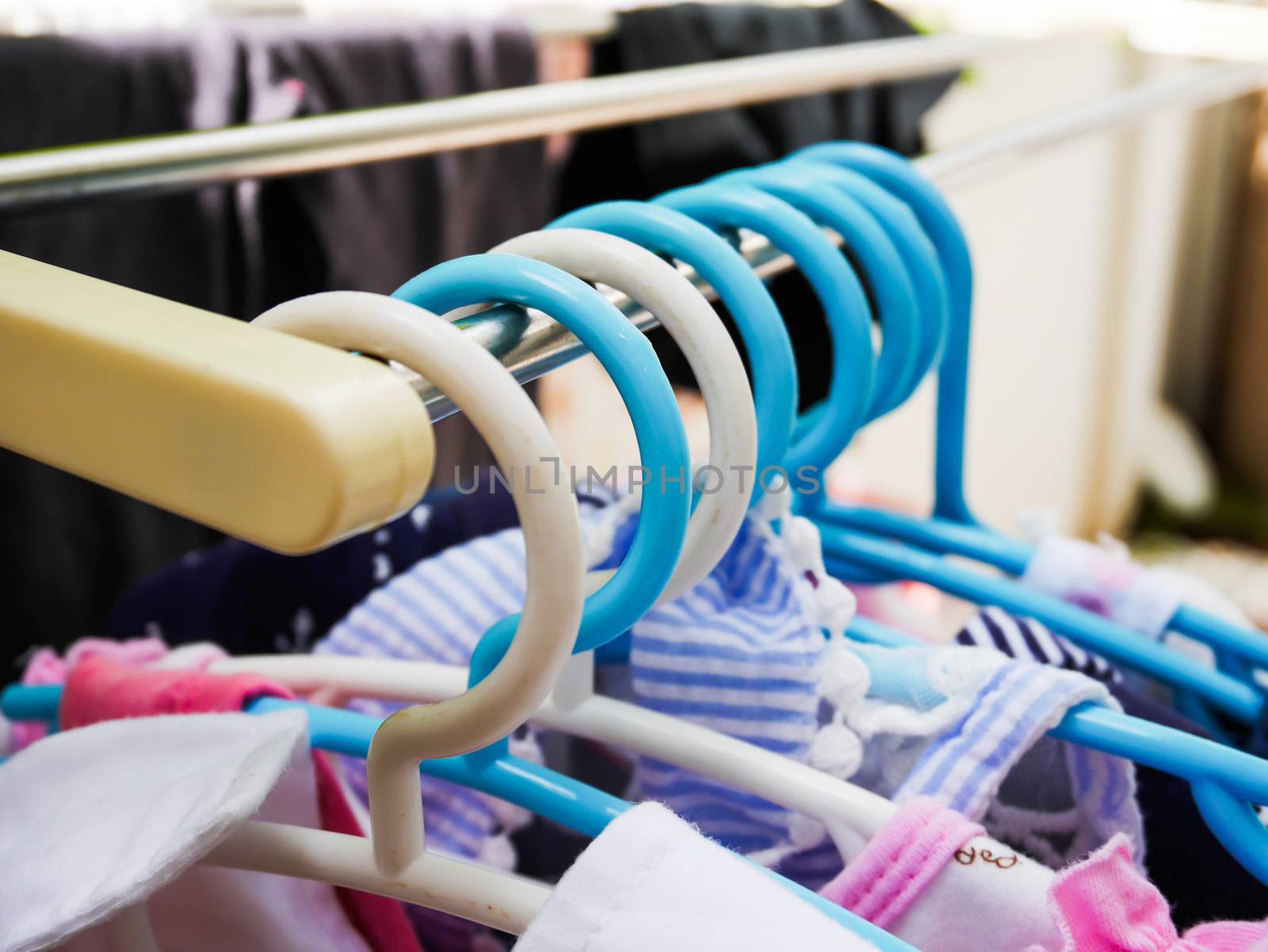 Plastic kid hangers on metal rack in home