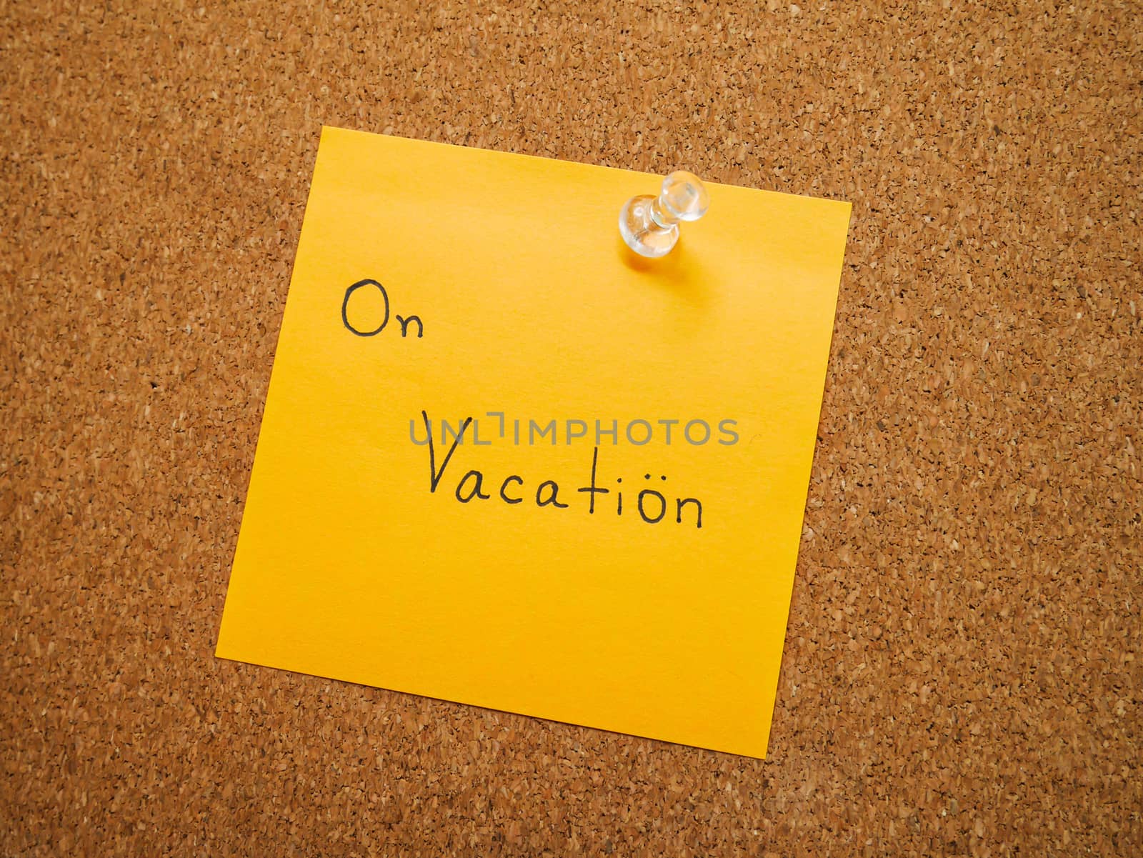 Text on vacation in orange post note and pin attach on wood board