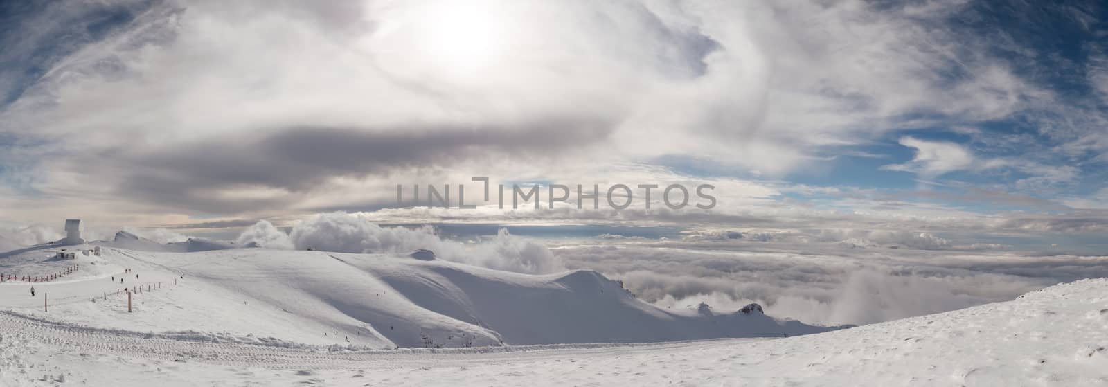 The top of the mountain Helmos in Kalavrita ski resort with snow and clouds in a sunny day