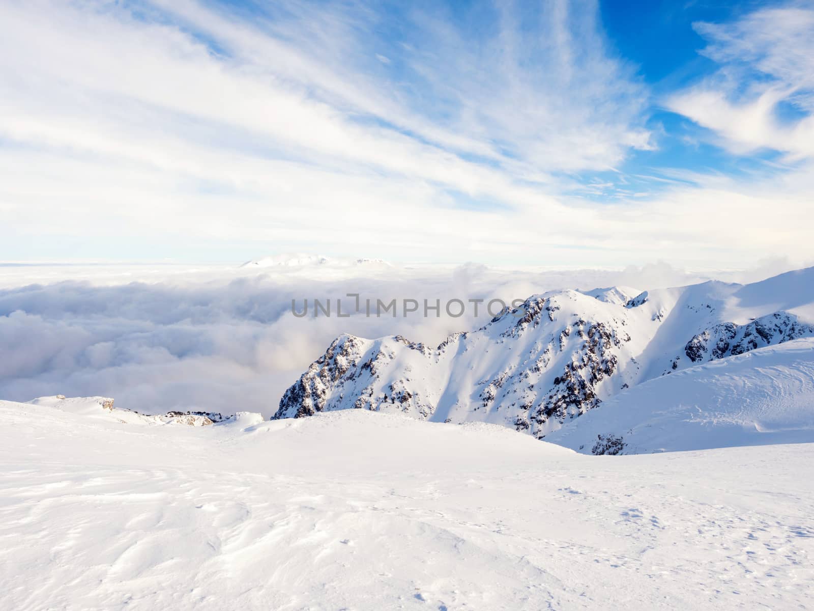 The top of the mountain Helmos in Kalavrita ski resort with snow and clouds in a sunny day