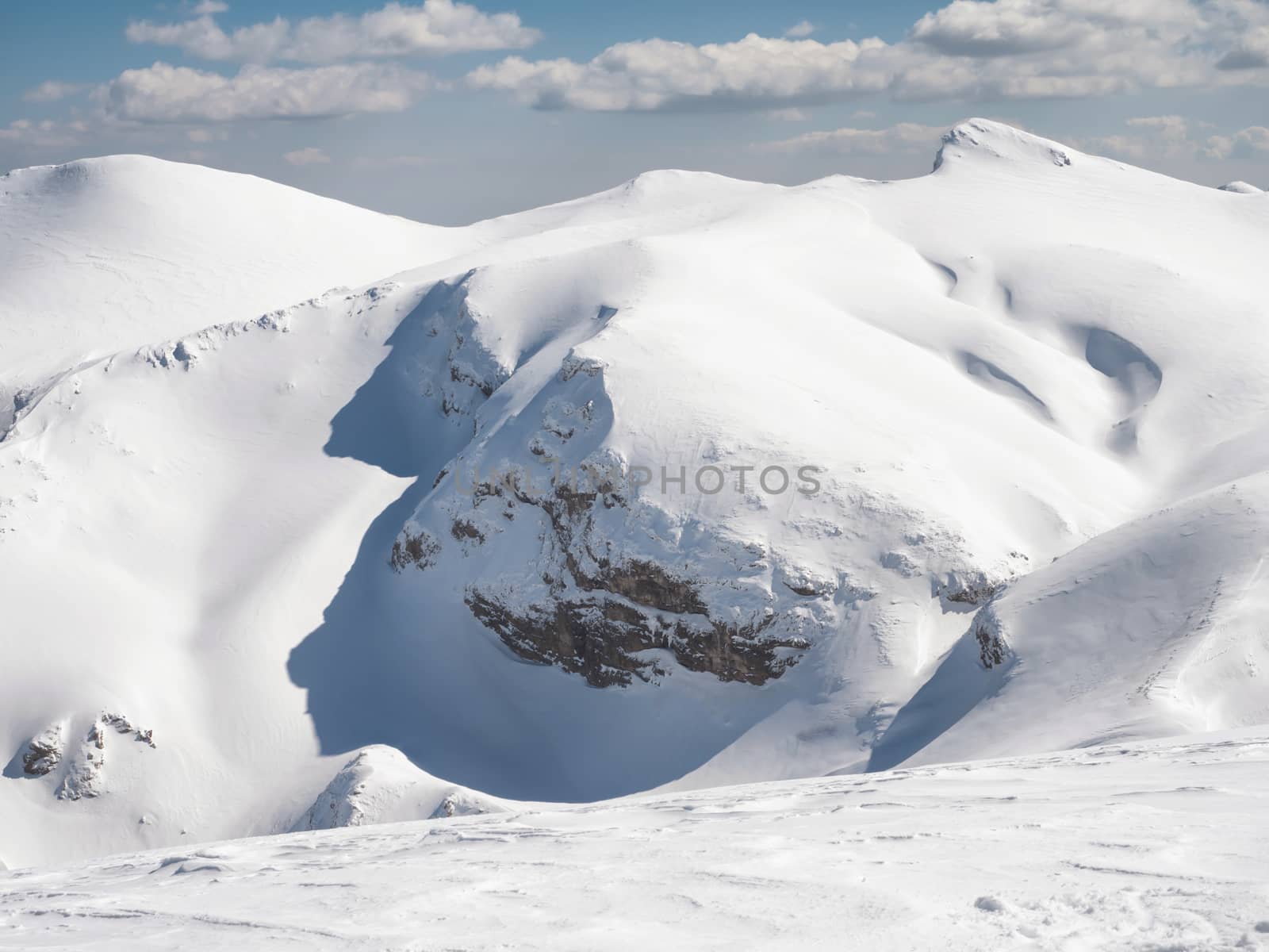 The top of the mountain Helmos in Kalavrita ski resort with snow and clouds in a sunny day