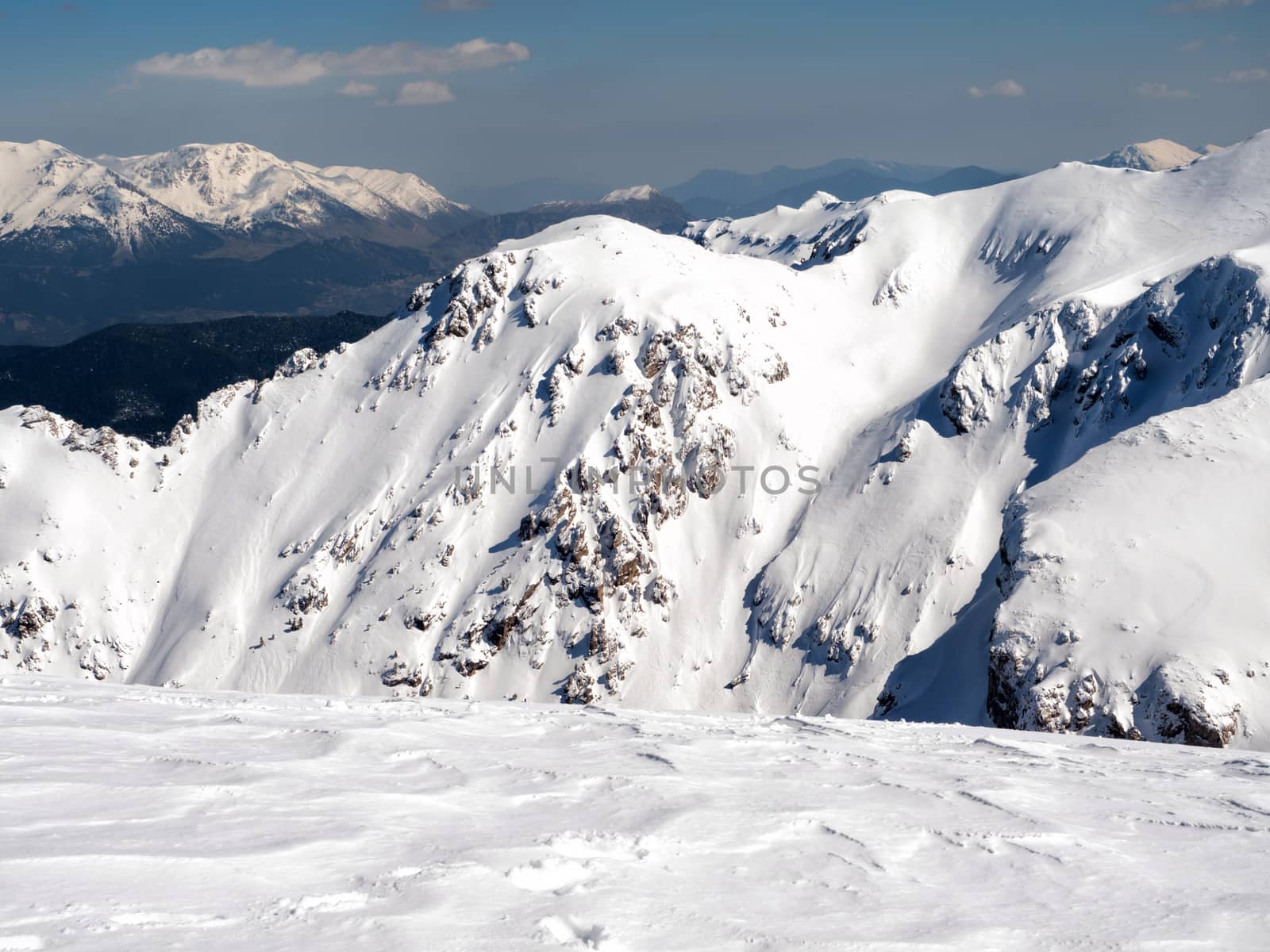 The top of the mountain Helmos in Kalavrita ski resort with snow and clouds in a sunny day