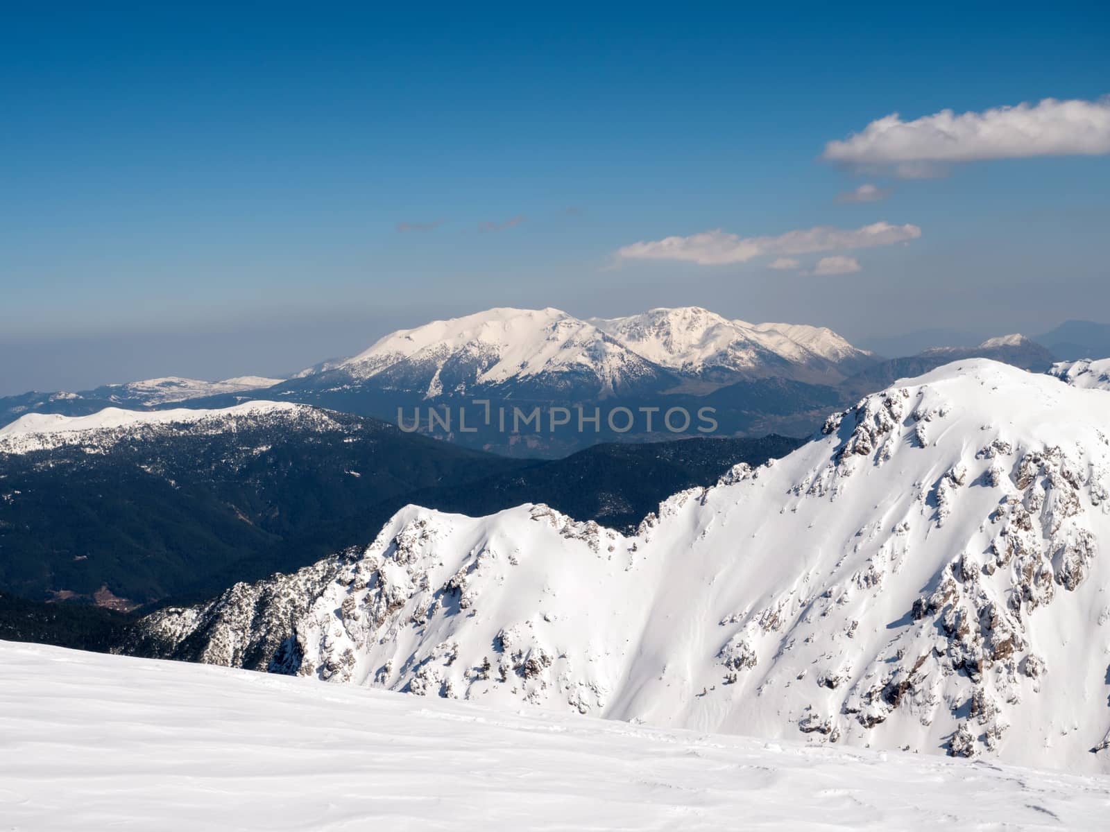 The top of the mountain Helmos in Kalavrita ski resort with snow and clouds in a sunny day