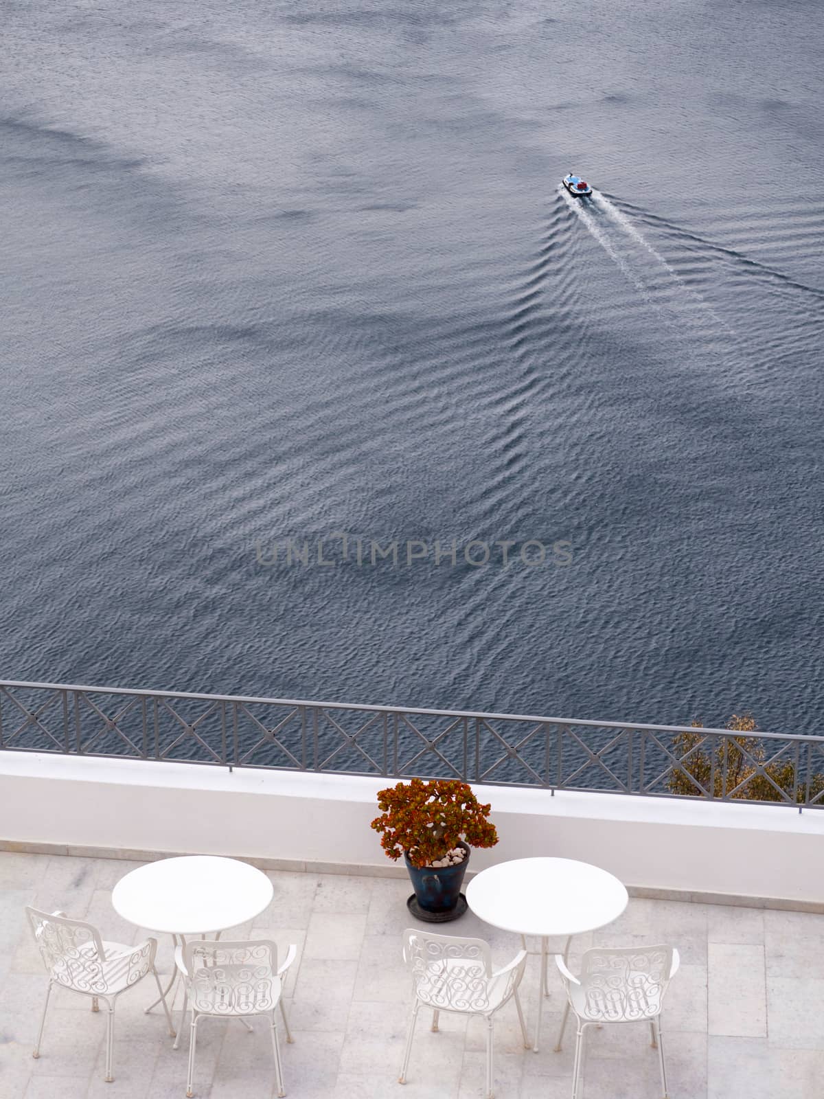 Balcony with tables and sea view with a boat passing in the background