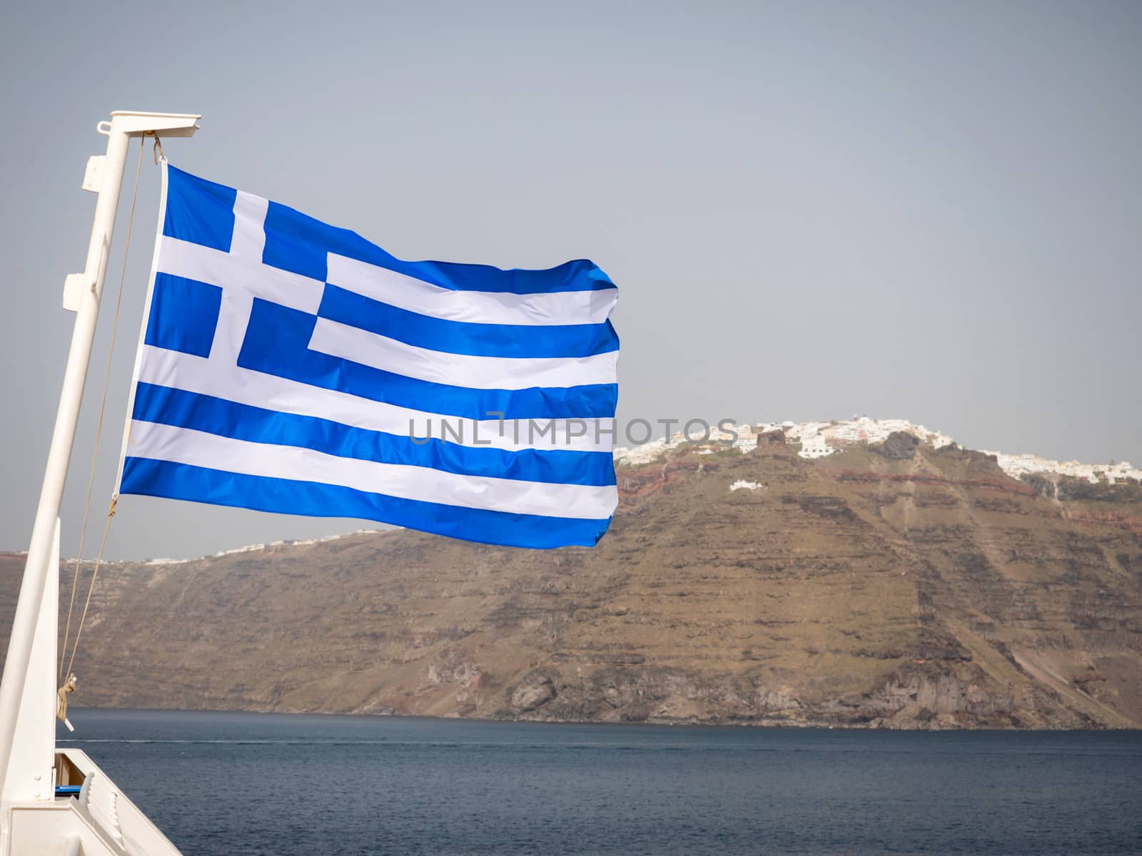 The Greek flag with Santorini island in the background