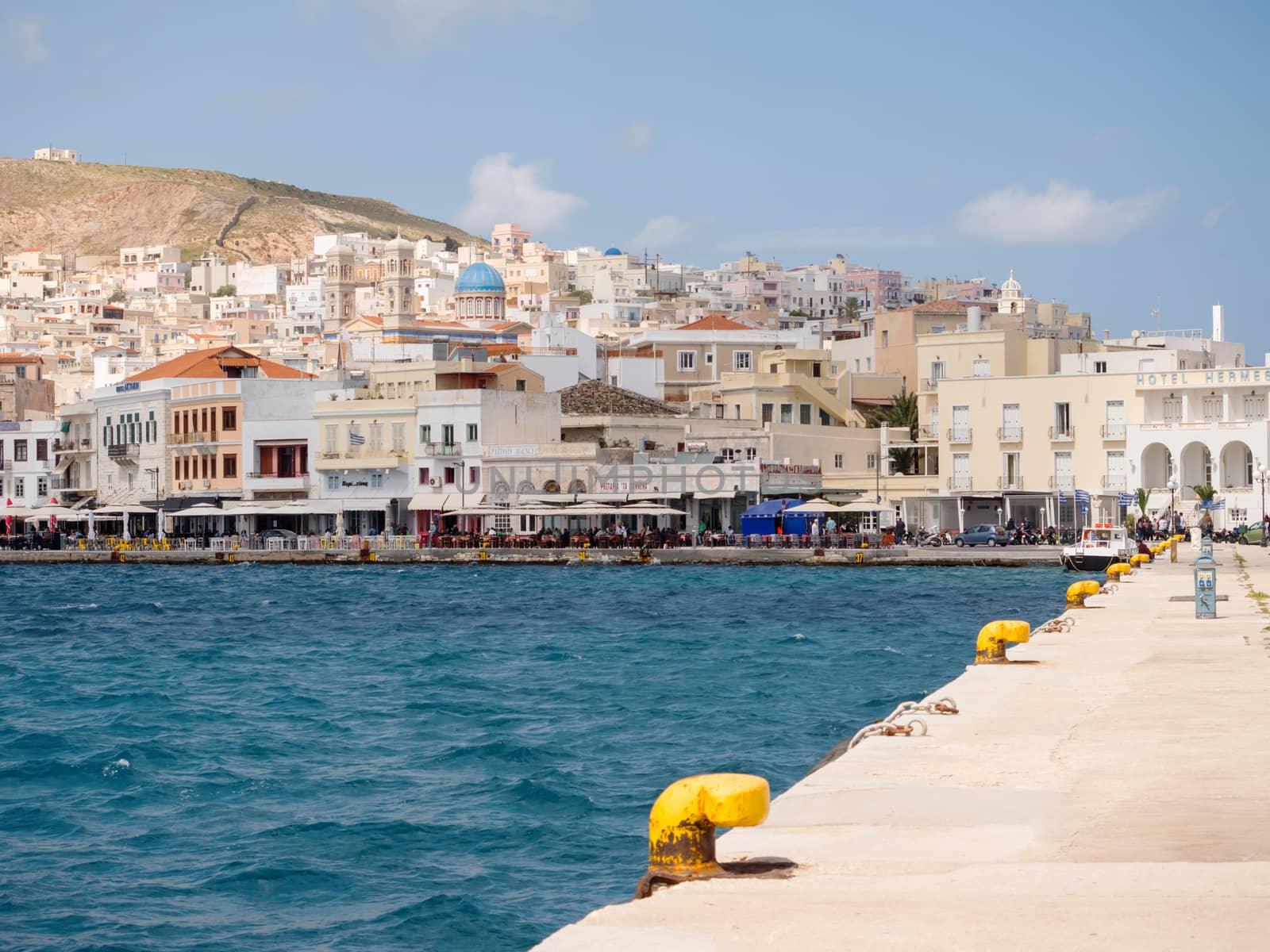 SYROS, GREECE - APRIL 10, 2016: View of Syros port with beautiful buildings and houses in a sunny day with clouds