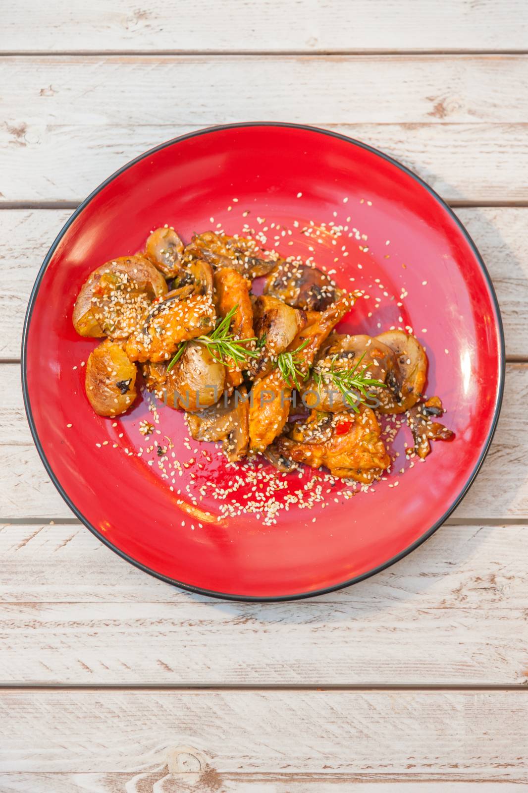 Chicken filet in sauce with smashed potatoes served on a red plate