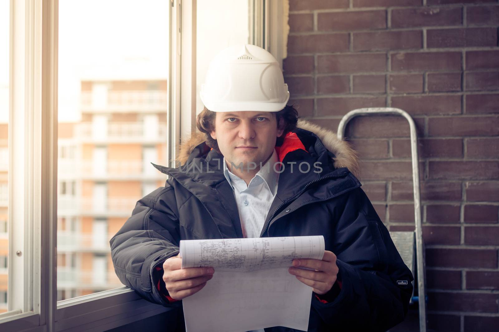 Portrait of an architect builder studying layout plans of building. Soft focus, toned