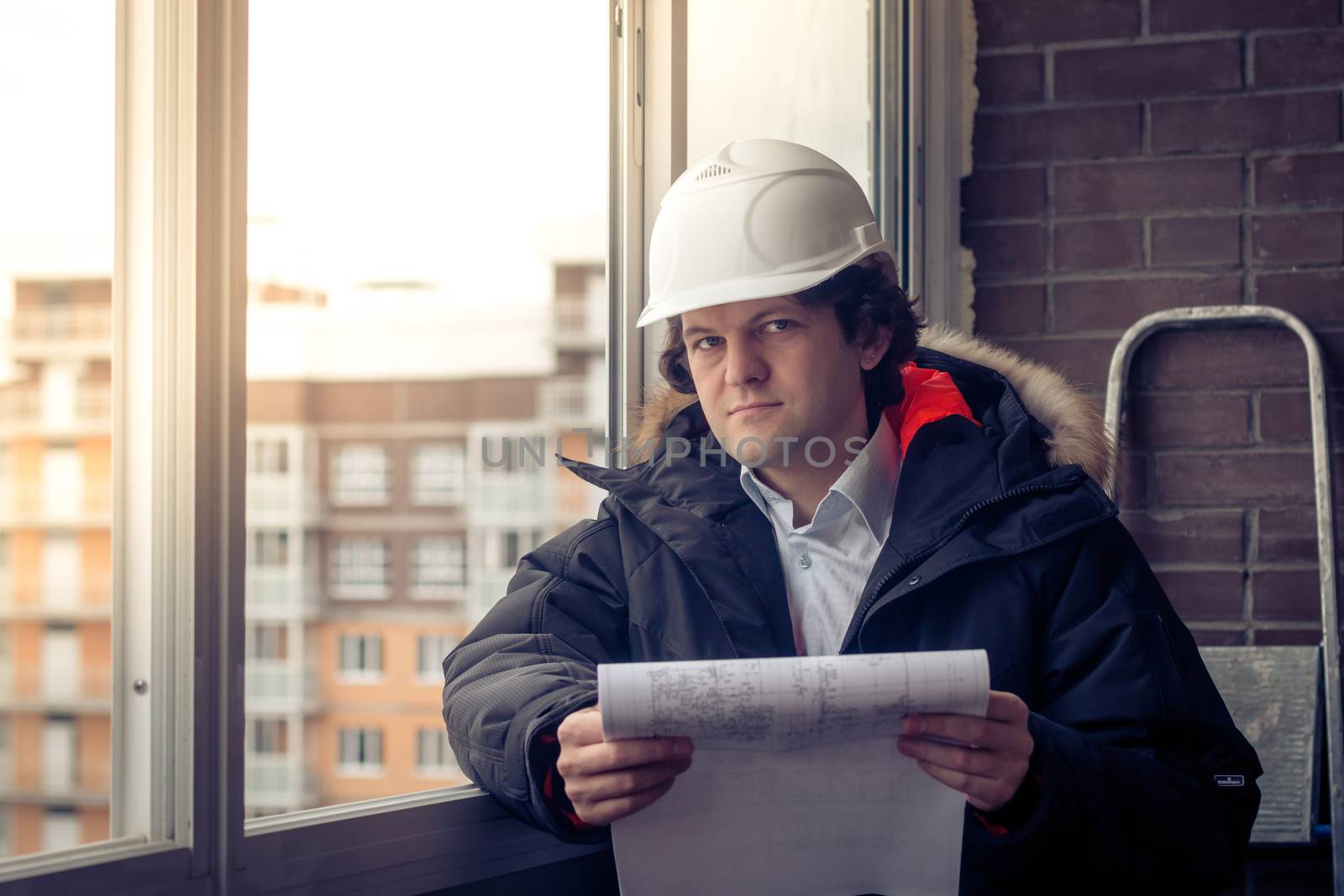 Pensive young man builder in hard hat standng and thinking. Soft focus, toned