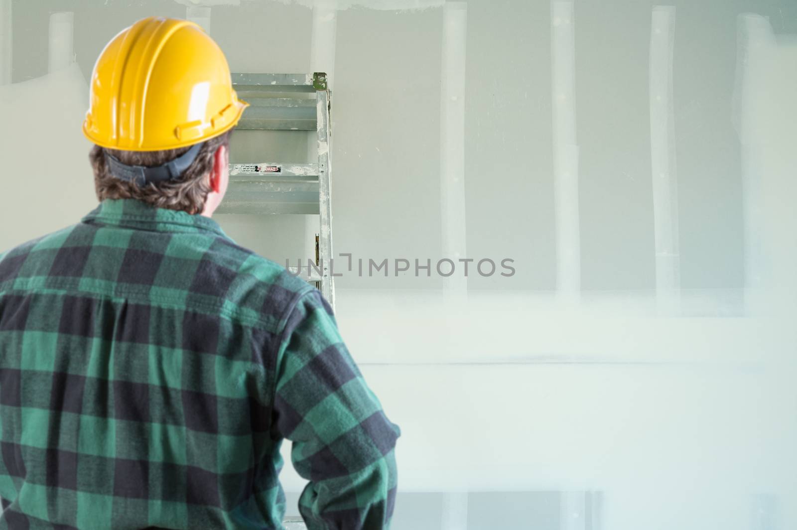 Contractor in Hard Hat Looking at Drywall. by Feverpitched