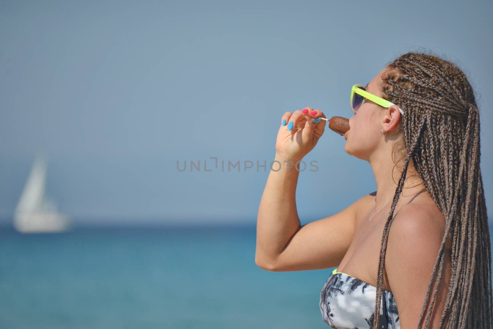A beautiful girl in her 30ies eating ice cream by the sea or ocean.