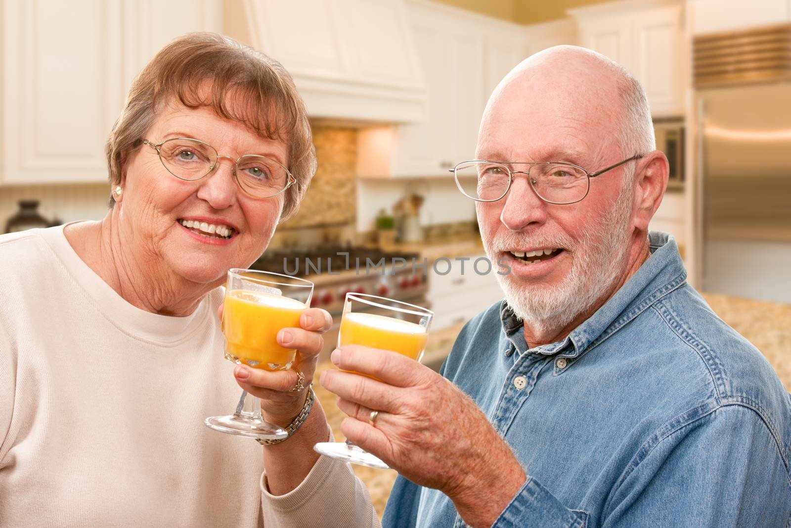 Happy Senior Couple with Glasses of Orange Juice Isolated on a White Background.