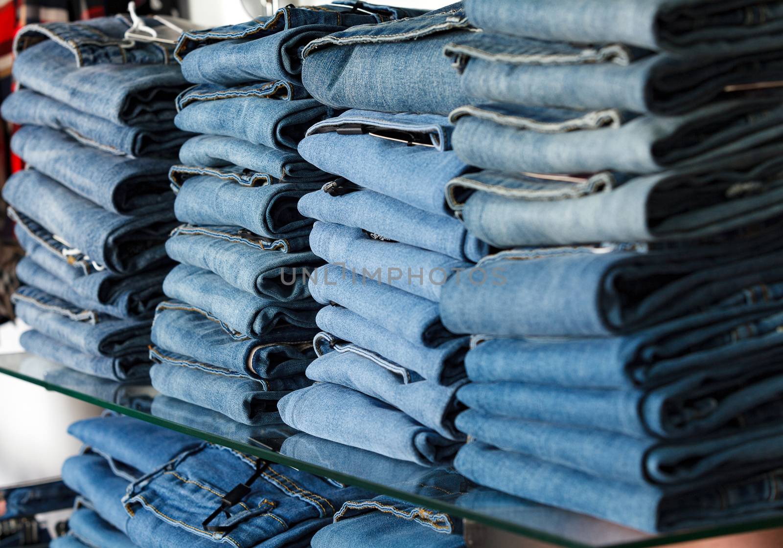 Closeup shot of stack of folded jeans in the fashion store by Nobilior