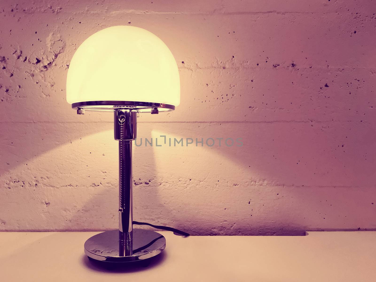 Lamp with round lampshade near concrete wall by anikasalsera