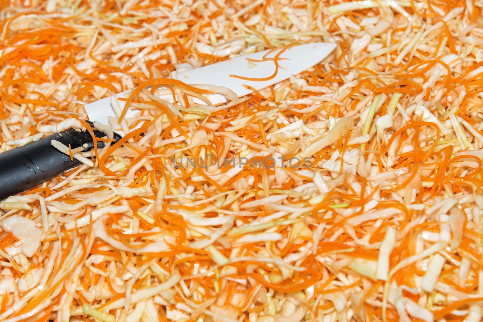 Preparing homemade sauerkraut - fermented cabbage and carrots, rustic winter food. Shredded cabbage, carrots, and knife.