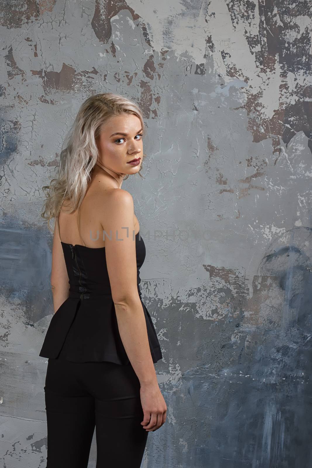 Portrait of a girl with long hair in youth clothes, Young beautiful girl near the wall her back